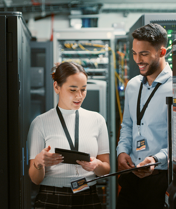 Male and female technicians working with devices in a network server room.